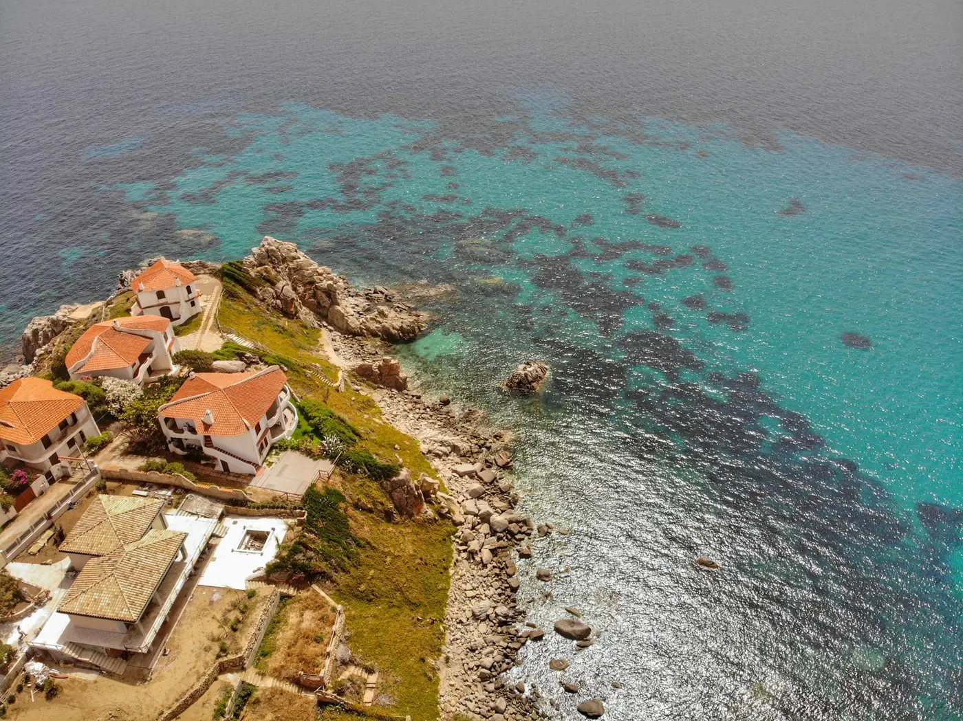Luchtfoto van huizen aan een rotsachtige kust bij helderblauw water