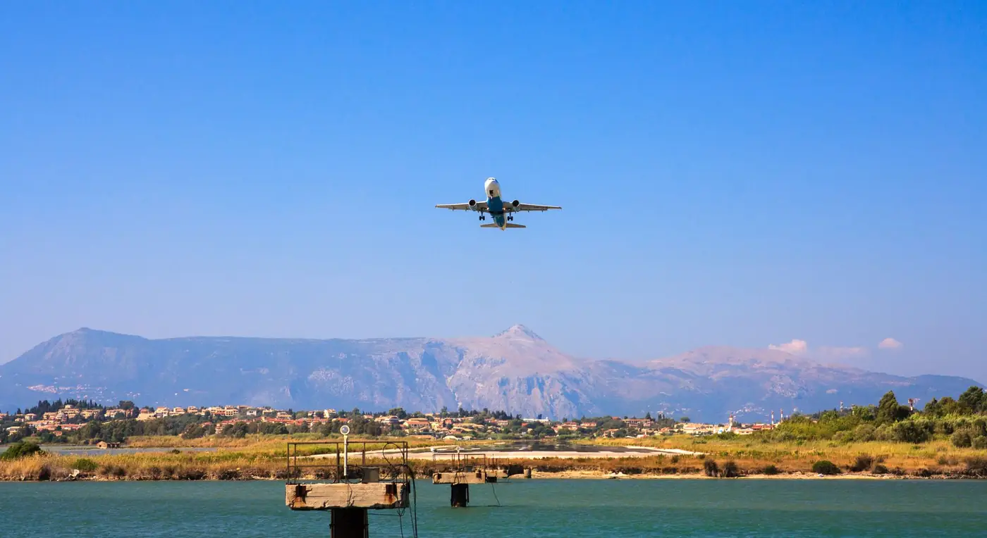 Vliegtuig in de lucht boven de kust en bergen van Corfu