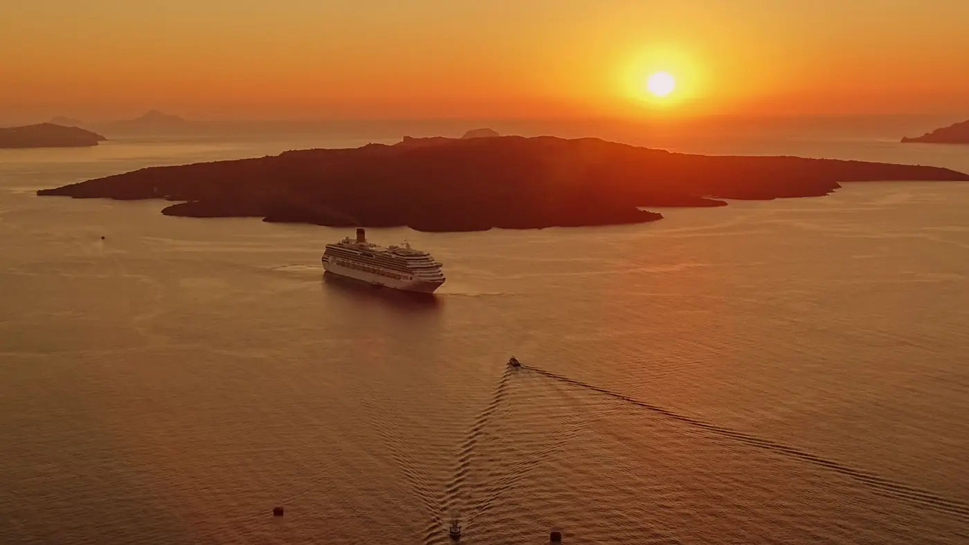 Cruiseschip voor de kust van Santorini bij zonsondergang