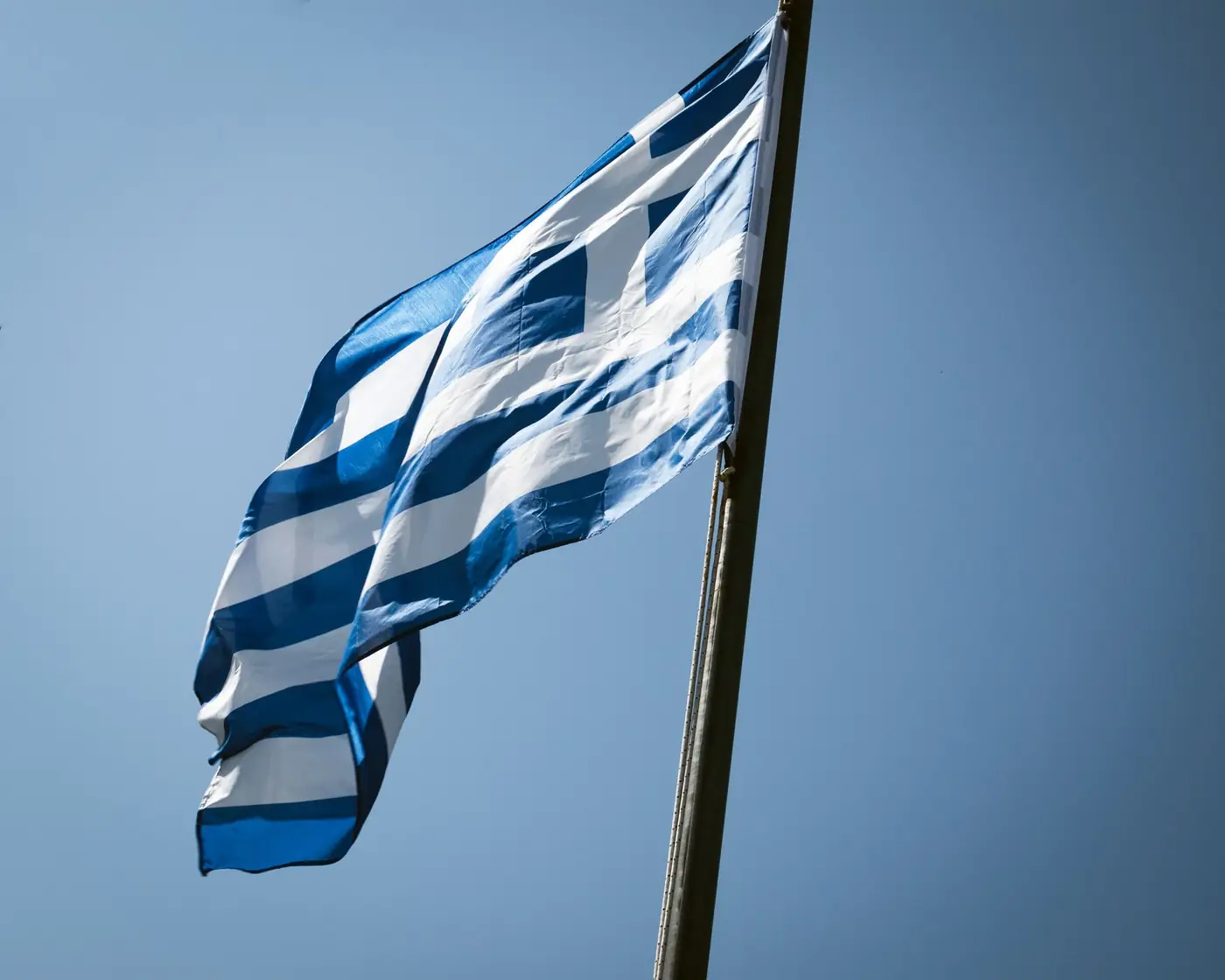 Griekse vlag wappert tegen een strakblauwe lucht