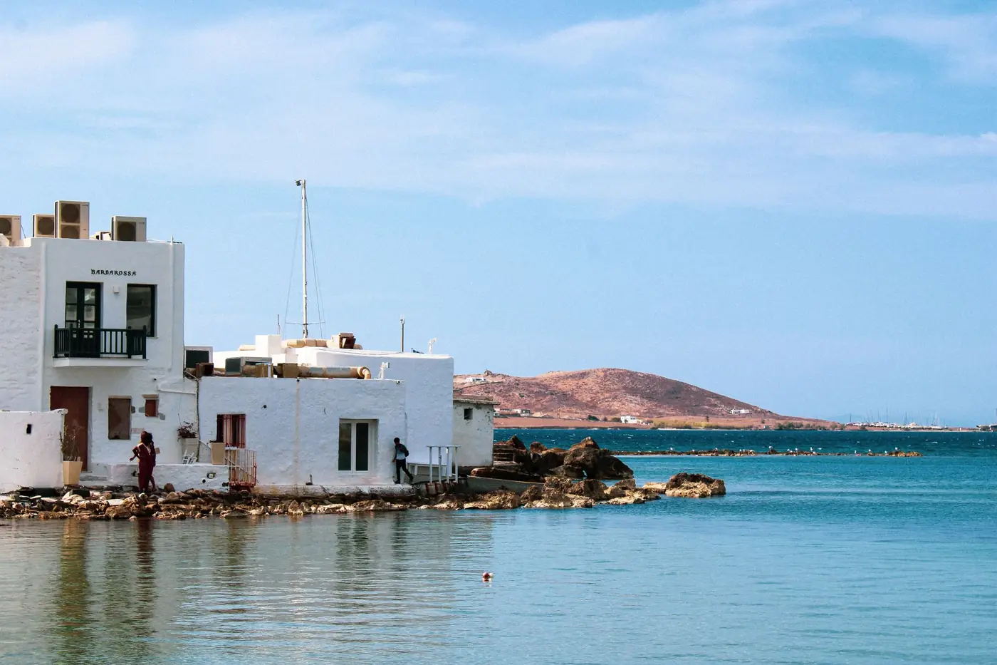 Witte gebouwen aan de kust van Naoussa op Paros met heuvels op de achtergrond