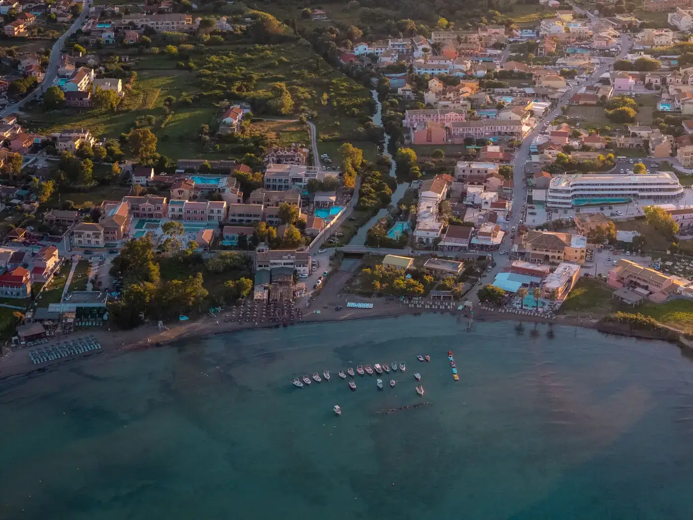 Stunning aerial photo showcasing a coastal village with vibrant buildings and boats at sunset in Corfu, Greece.