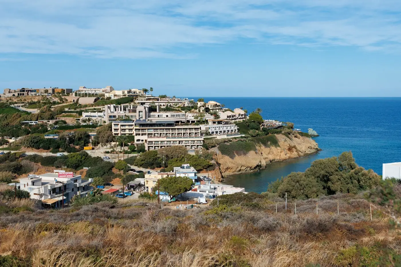Explore the stunning coastline of Crete, Greece, showcasing a vibrant resort village and crystal-clear Mediterranean wat