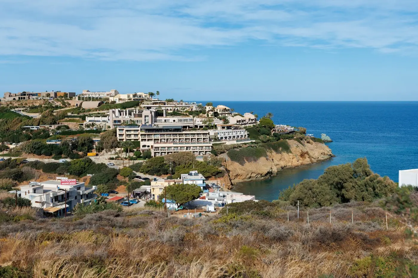 Explore the stunning coastline of Crete, Greece, showcasing a vibrant resort village and crystal-clear Mediterranean waters.