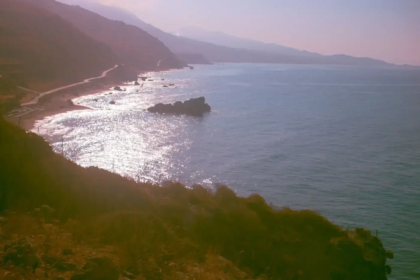 Breathtaking coastal landscape in Agios Nikolaos, Greece, with shimmering sea and rugged cliffs.