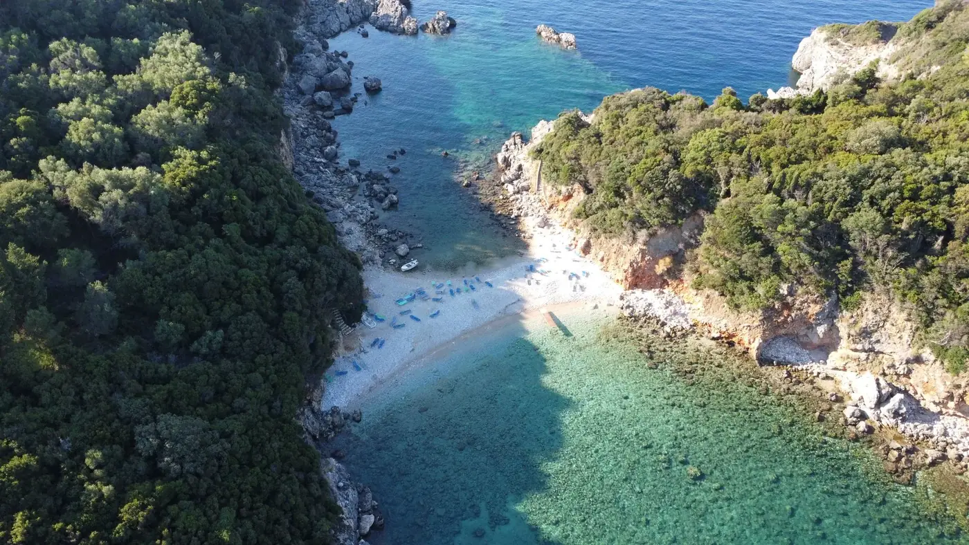 Scenic aerial view of a hidden beach on Corfu, Greece with vibrant waters and lush greenery.