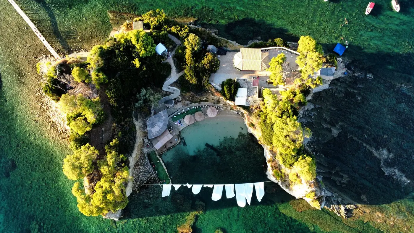 A stunning aerial view of a secluded beach resort in Zakynthos, Greece, surrounded by lush greenery and crystal-clear wa