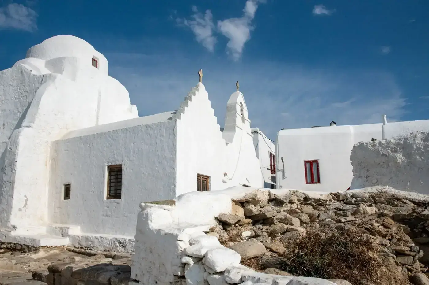 Stunning view of a traditional whitewashed church in Mykonos, Greece under a clear blue sky.