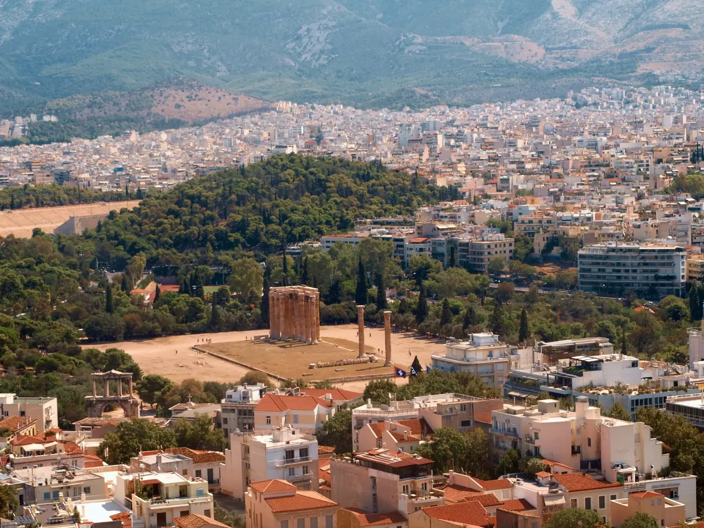 Explore the stunning aerial view of Athens including the Temple of Olympian Zeus, a historic landmark in Greece.
