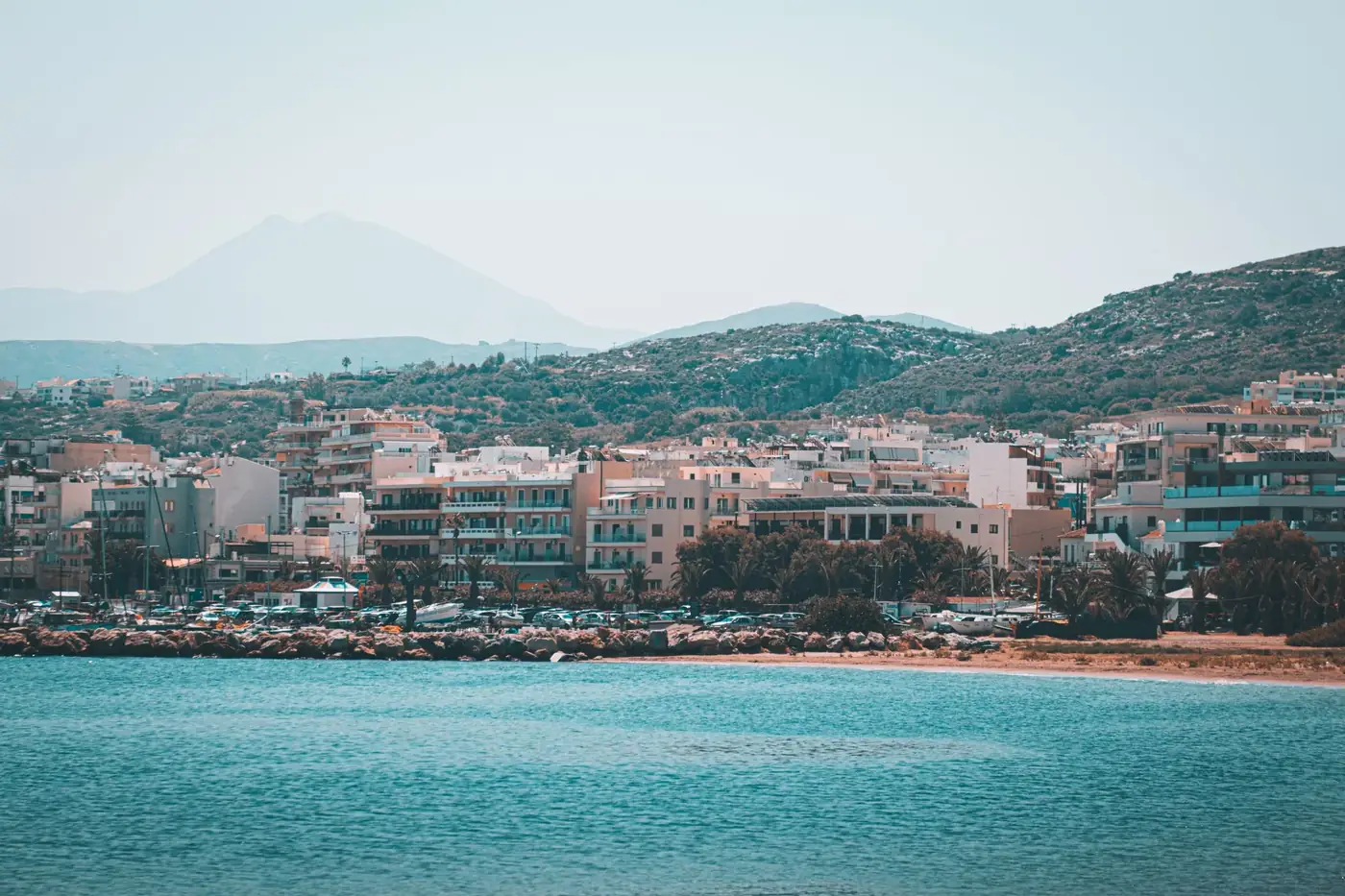 Capture the stunning coastal cityscape of Rethymno, Crete, with mountains and sea.