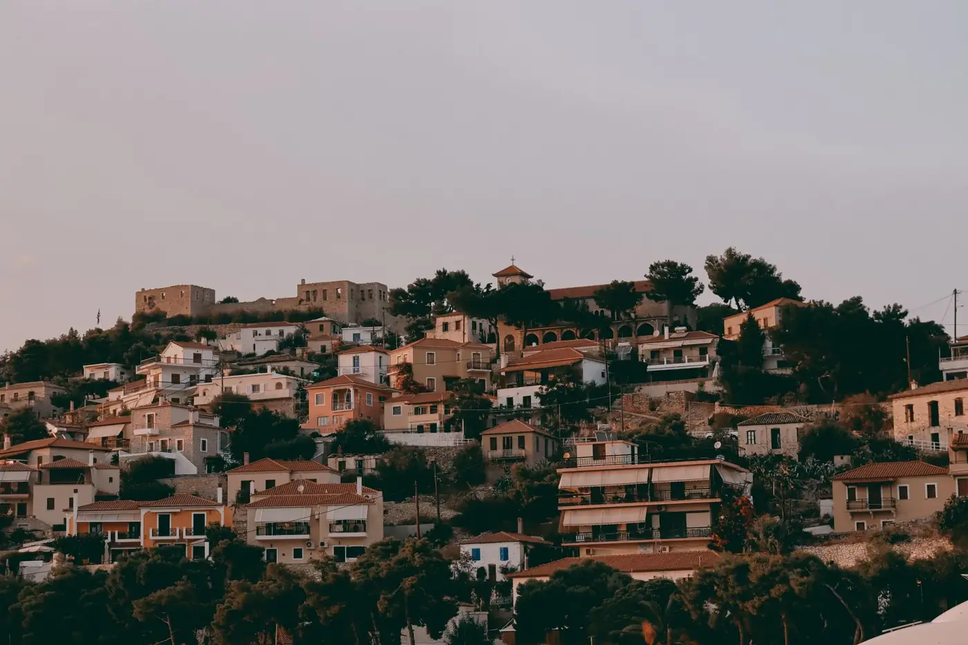 Scenic view of Paralio Astros village, Greece, with its charming houses under a warm sunset sky.