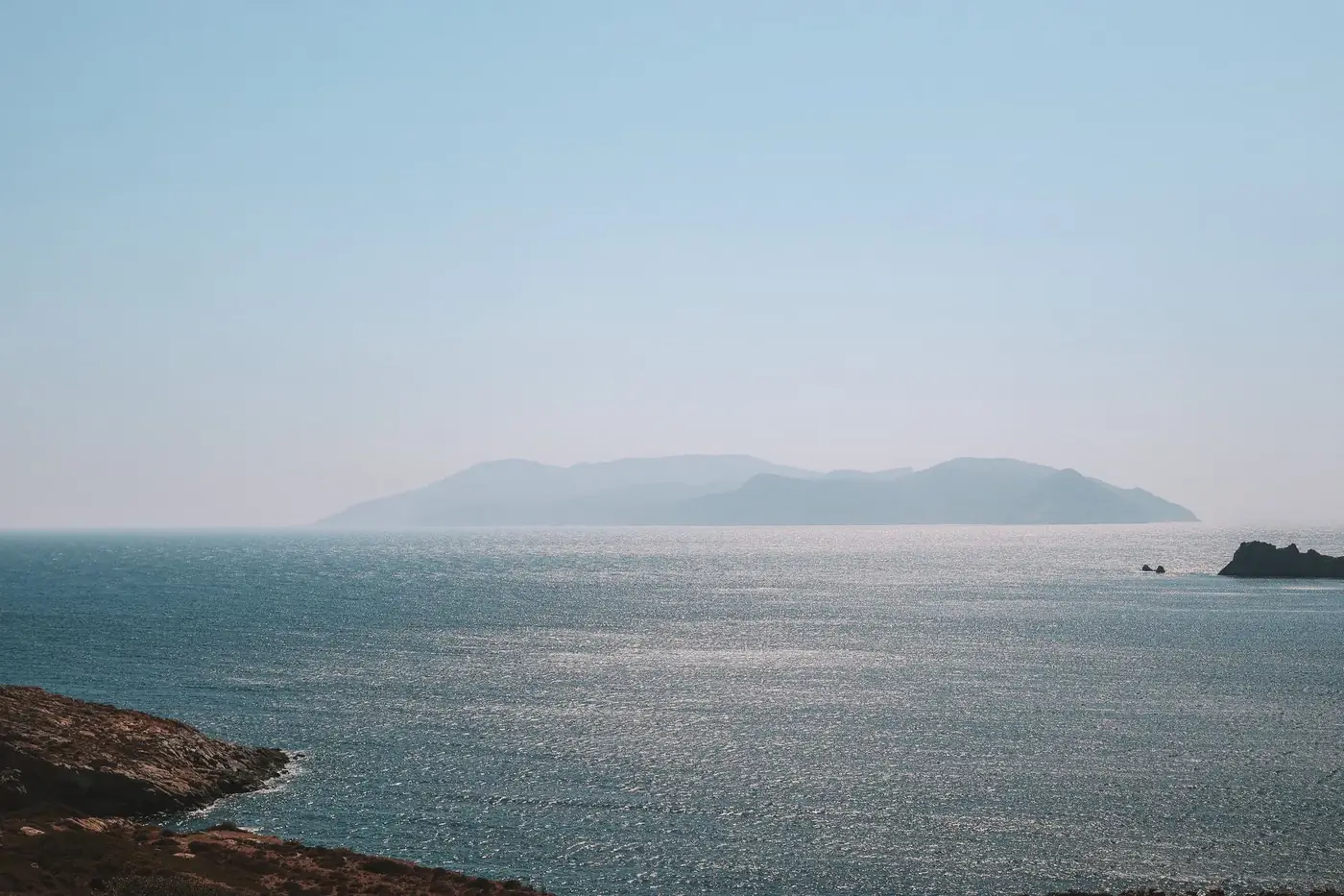 Peaceful view of the Aegean Sea with distant Greek islands under a clear sky.