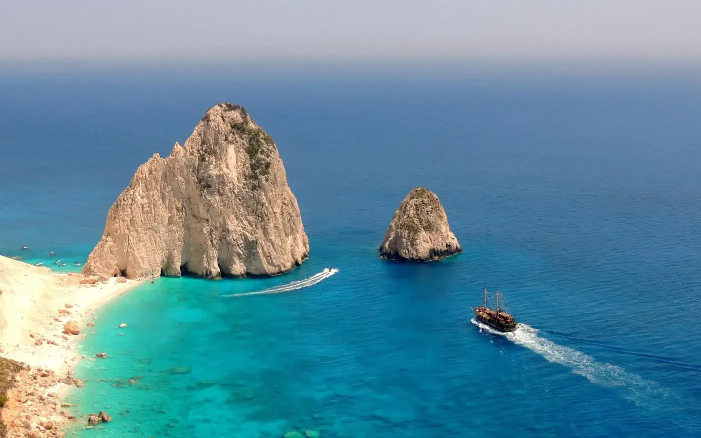 Aerial view of boat navigating the turquoise waters near rock formations off Zakynthos, Greece.
