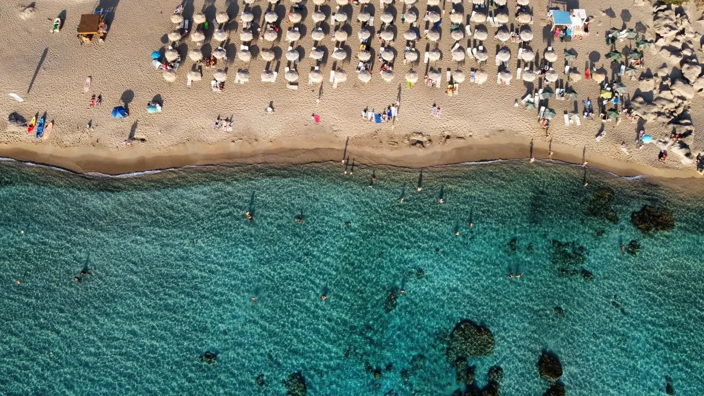 Aerial view of Chania beach, Greece with umbrellas and turquoise water.