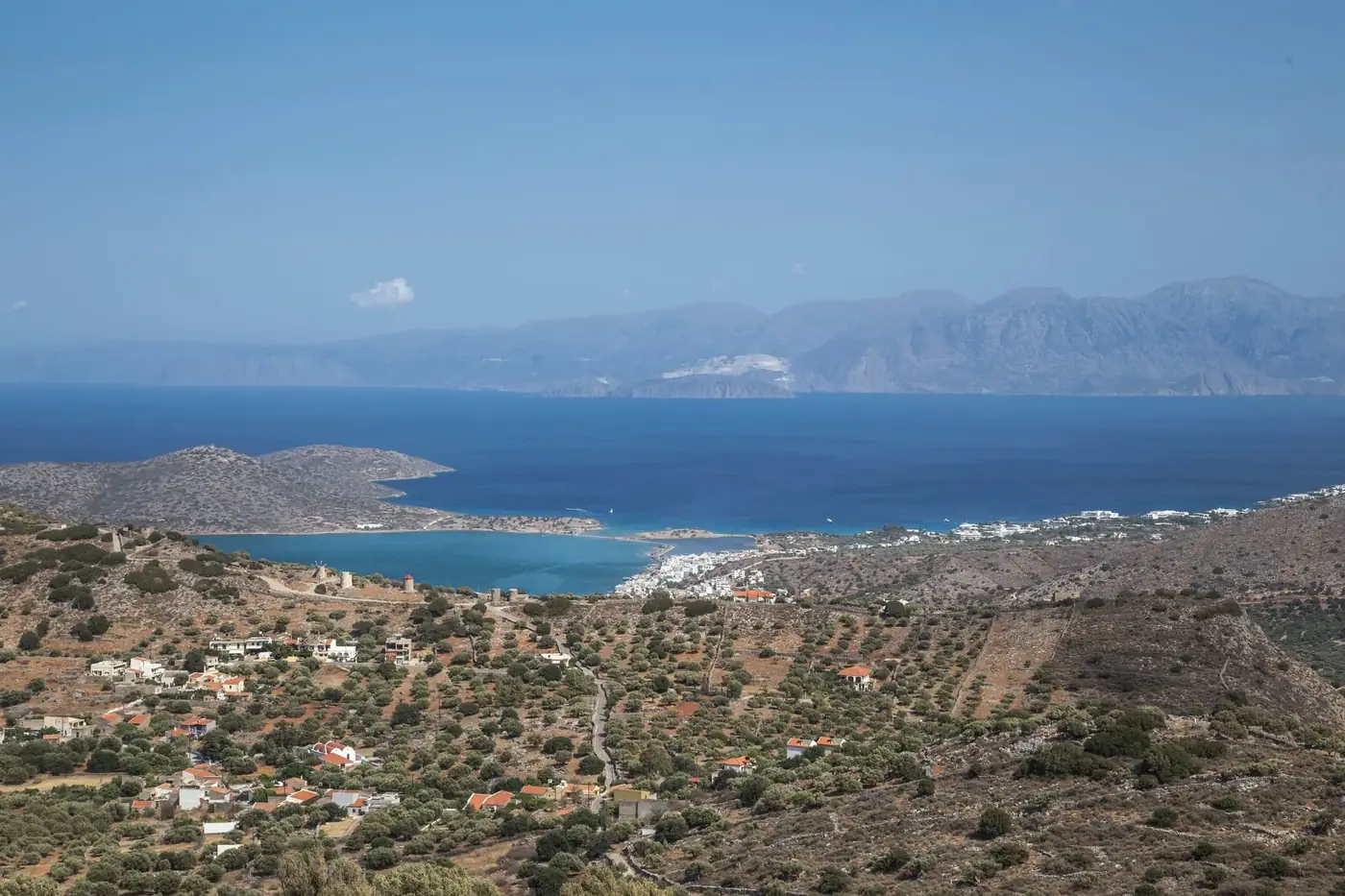 Amazing view of hilly coastal settlement in Crete island near azure calm sea under blue sky on clear summer weather
