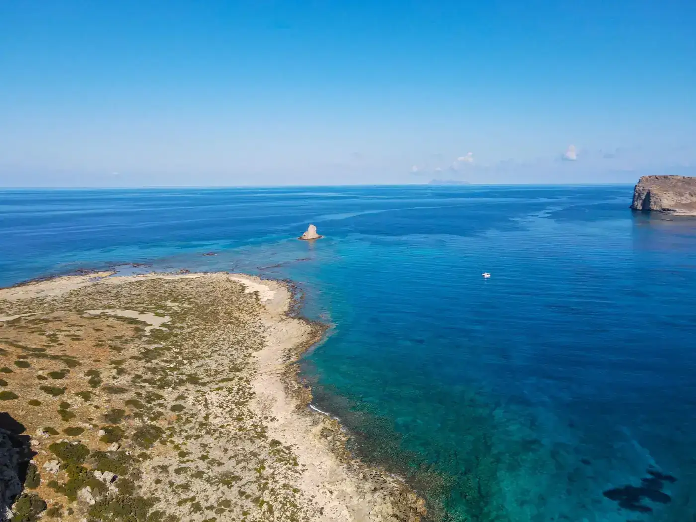 Aerial shot of a serene tropical coastline with clear blue waters and rocky shores.