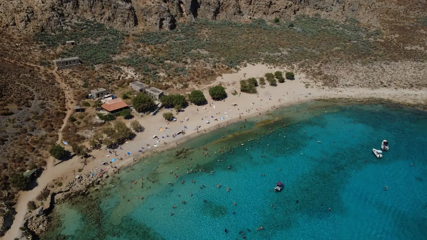 Stunning aerial shot of a vibrant beach with turquoise waters in Crete, Greece.
