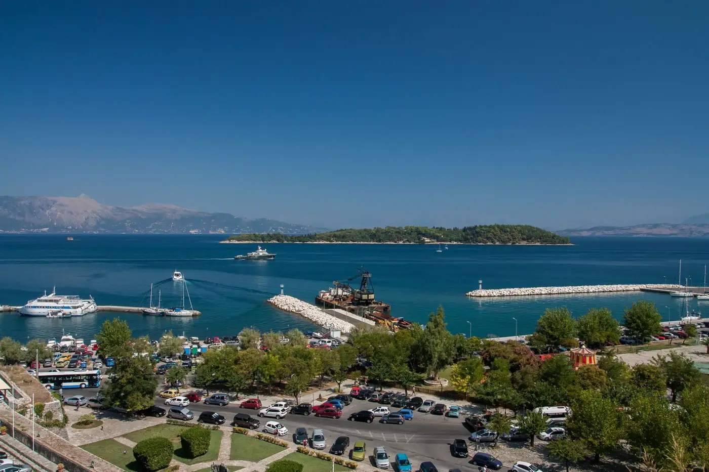 A beautiful aerial view of Corfu harbor with boats and blue water under clear skies.