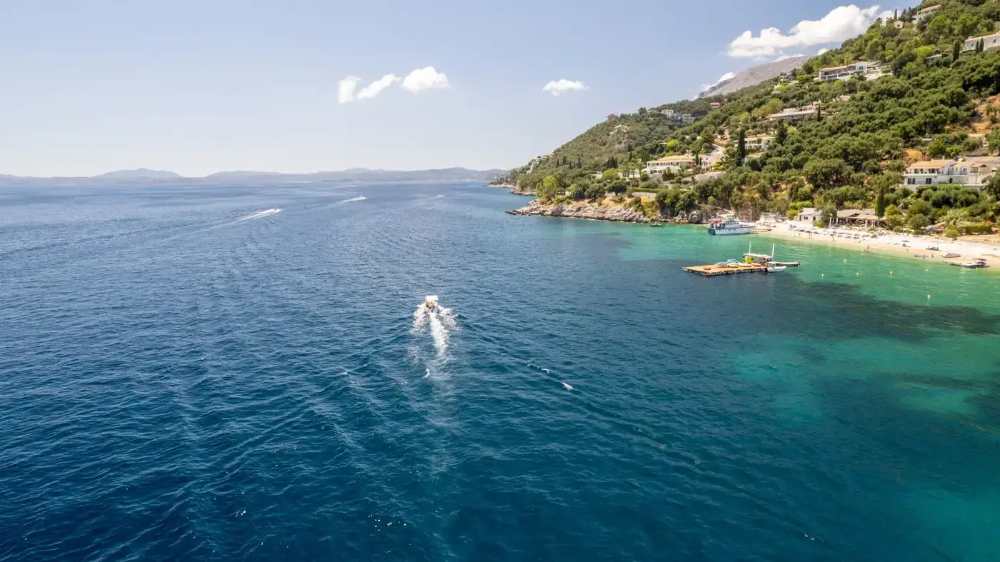 Scenic view of Corfu's coastline featuring a boat on the blue sea under a clear sky.