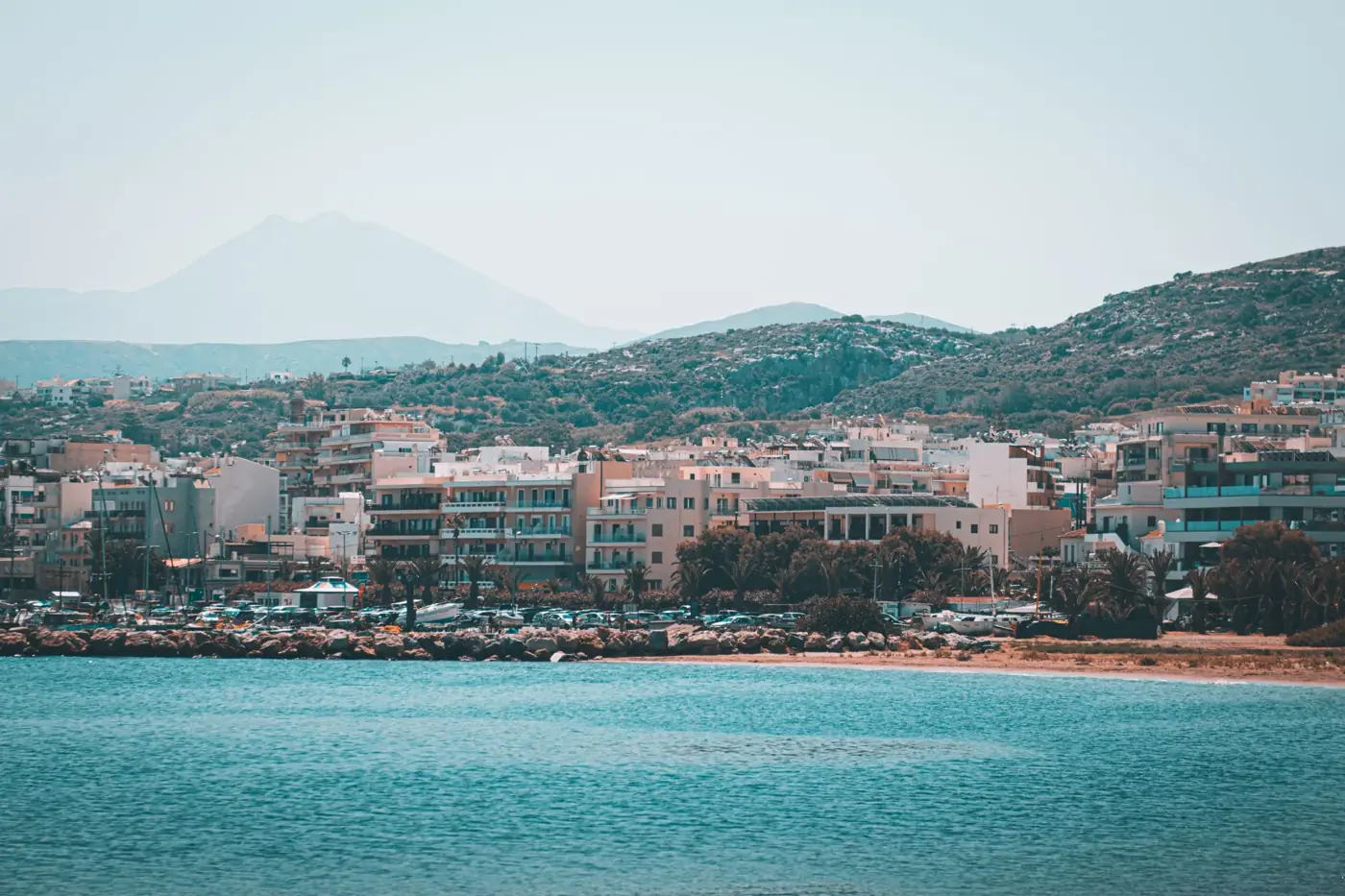 Capture the stunning coastal cityscape of Rethymno, Crete, with mountains and sea.