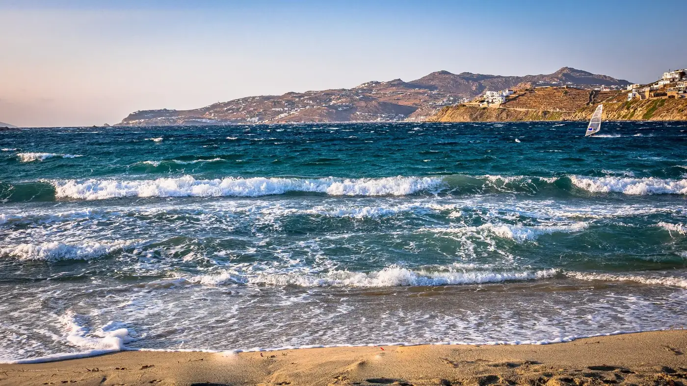 Vibrant waves hitting the sandy beach on a summer day at Mykonos, Greece.