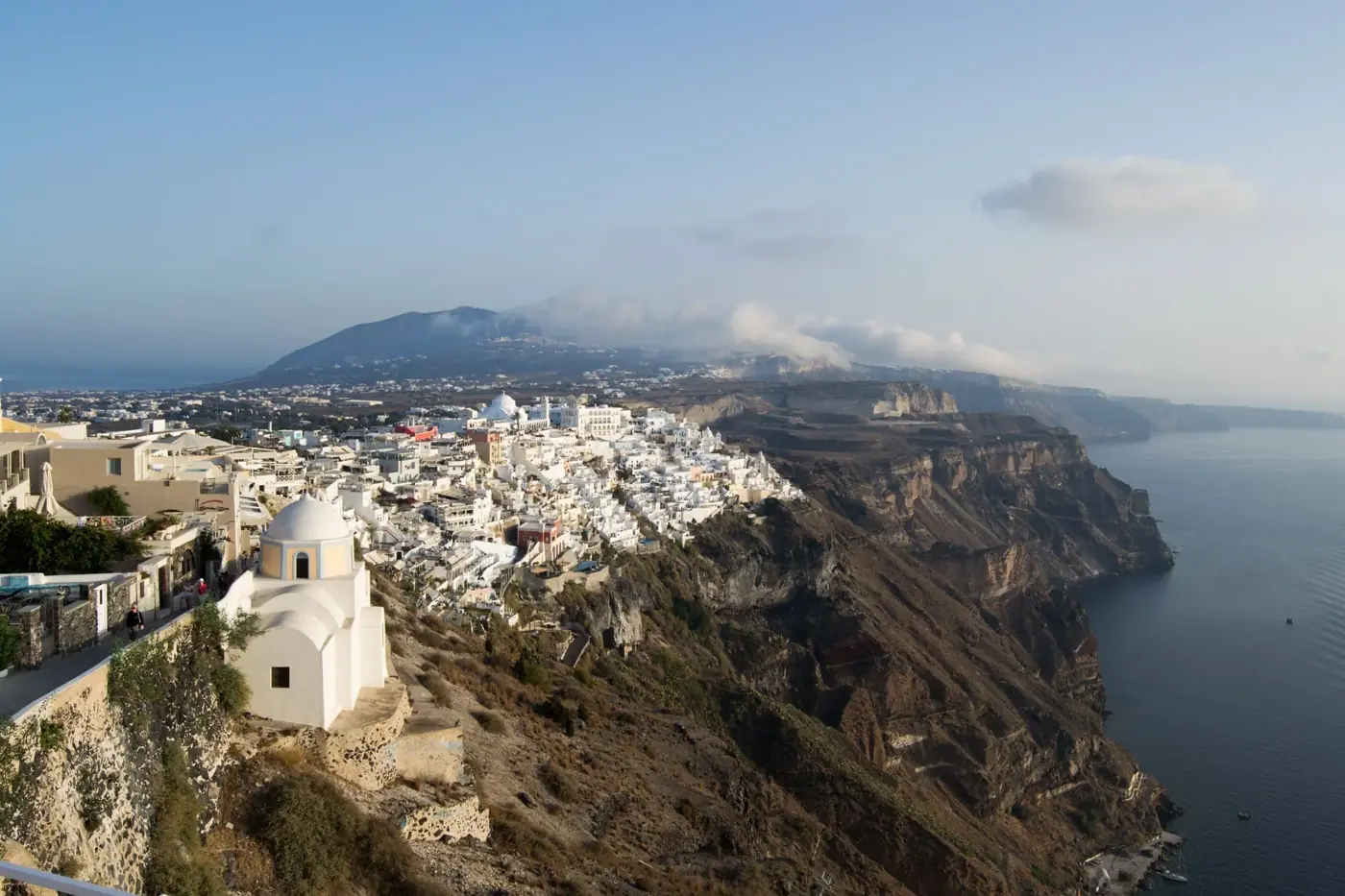 Breathtaking aerial view of Santorini's white buildings perched on a cliff overlooking the Aegean Sea.