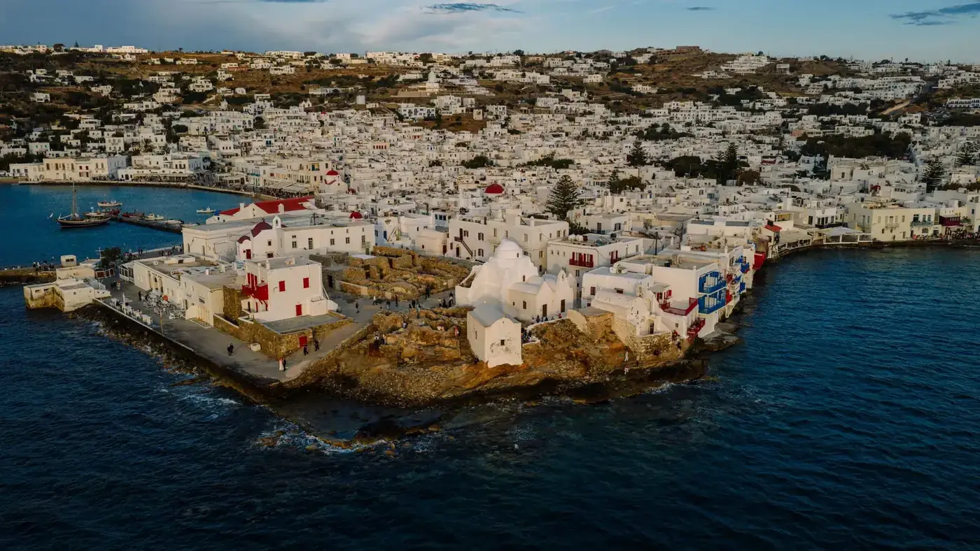 Stunning aerial view of Mykonos town with whitewashed buildings and blue sea, showcasing Greek island architecture.
