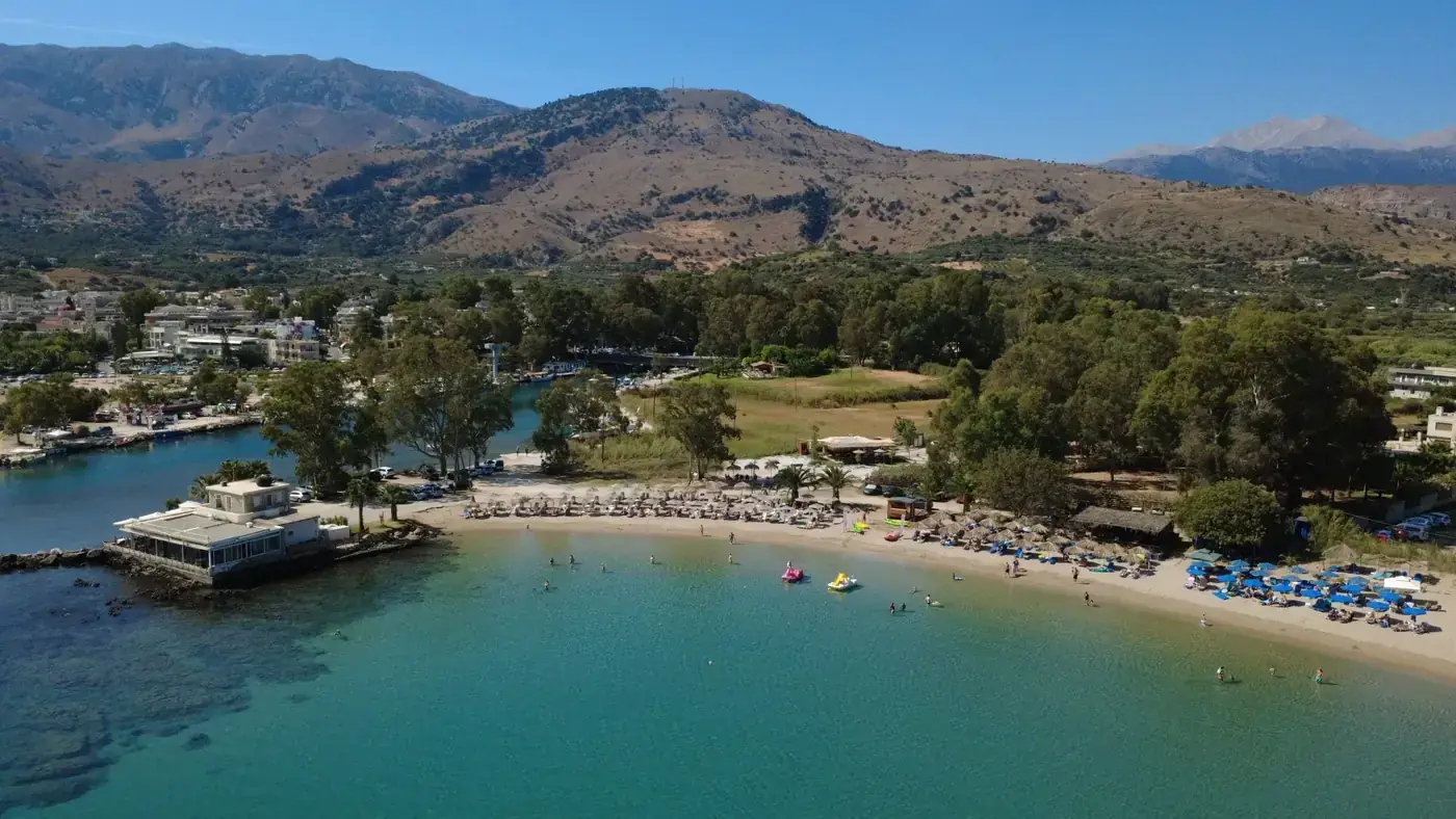A stunning aerial shot of Georgioupoli beach with turquoise waters and mountain backdrop, Greece.