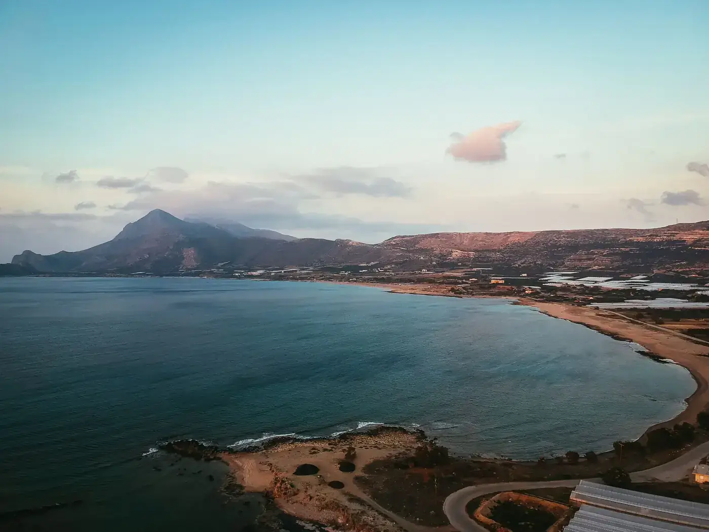 A breathtaking aerial view of Limeniskos coastline in Greece during sunset, showcasing mountains and the serene sea.