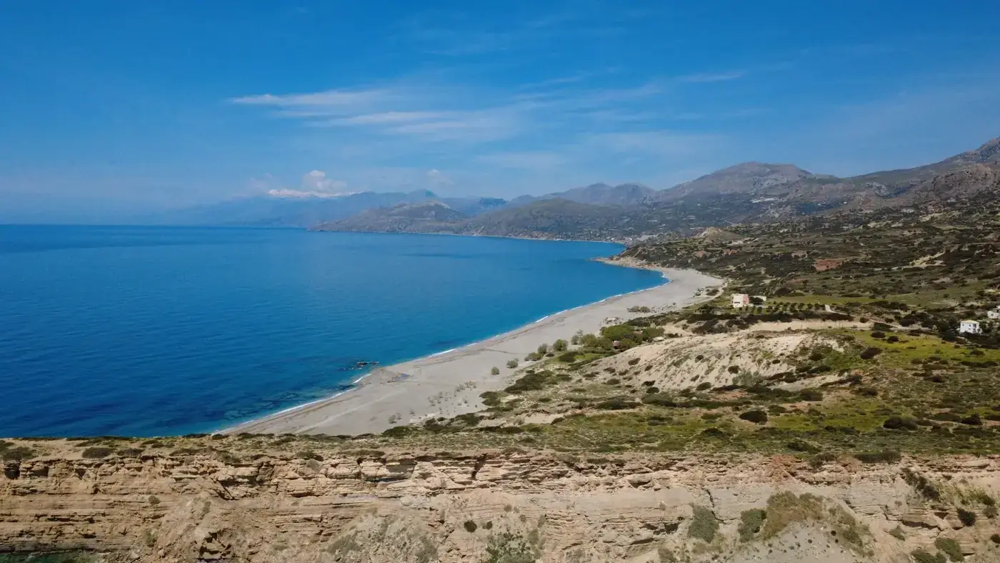 Aerial view of the stunning coastline of Triopetra Beach in Crete, Greece under a bright blue sky.