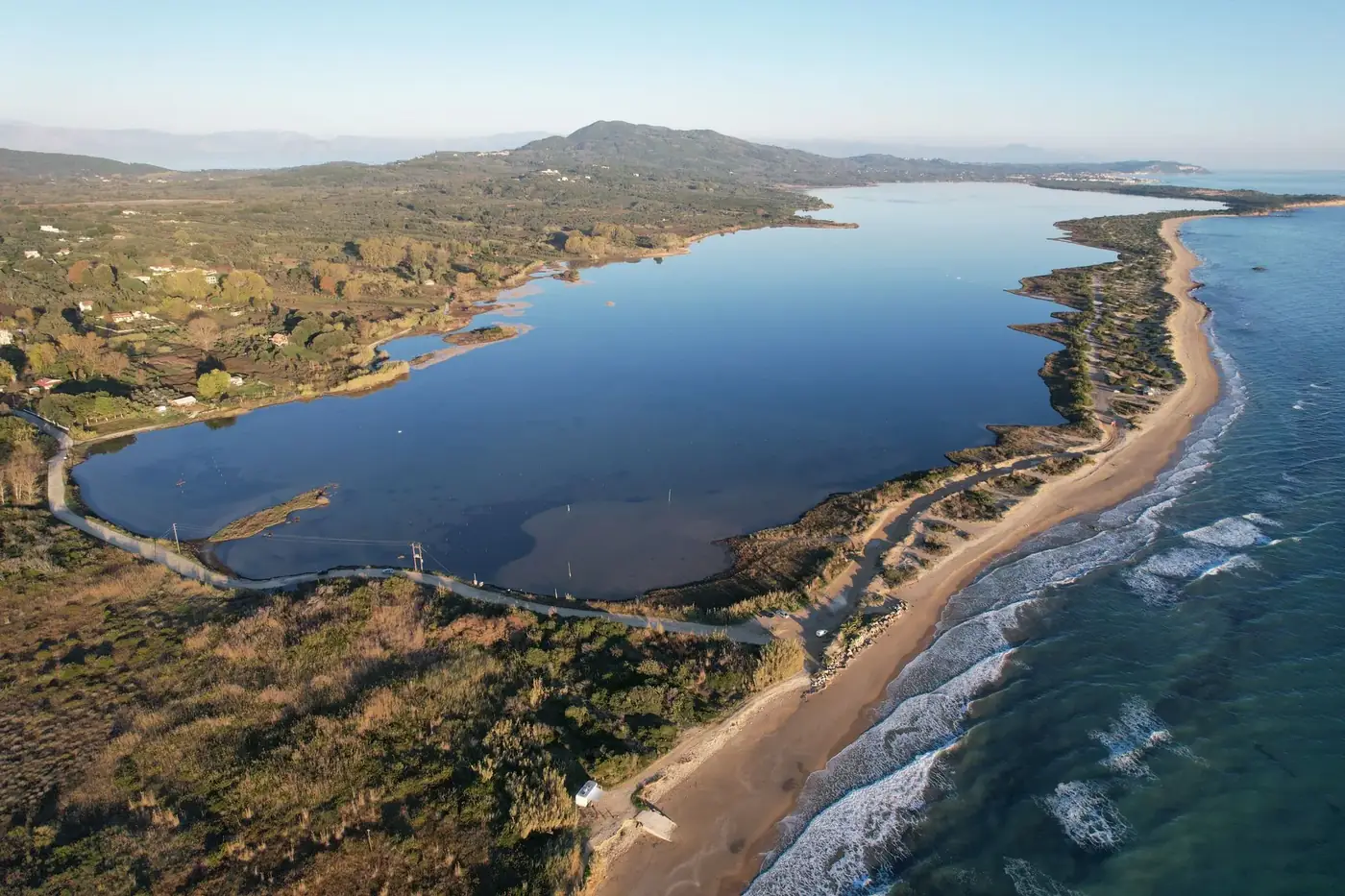 Breathtaking aerial view of Corfu's coastline with a serene lagoon and waves.