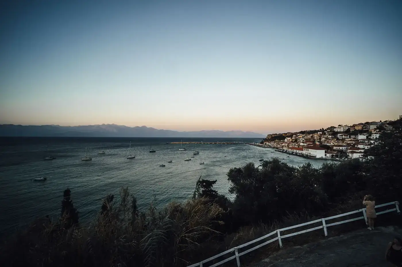 Breathtaking sunset over Koroni, Greece, featuring coastal village and yachts on the sea.