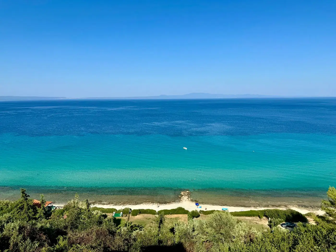 A stunning aerial view of the turquoise Aegean Sea with clear skies and verdant shoreline.