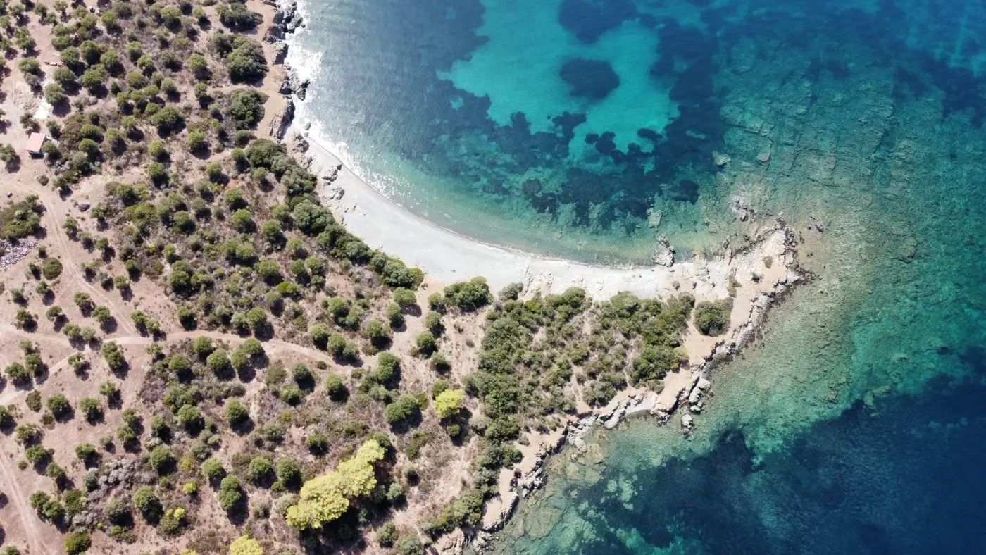 A stunning aerial shot of a Greek coastline with clear blue waters and lush greenery.