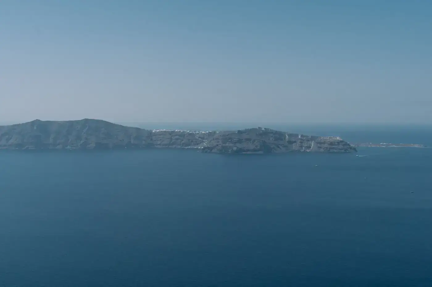 Serene aerial view of Santorini island surrounded by crystal blue waters under a clear sky.