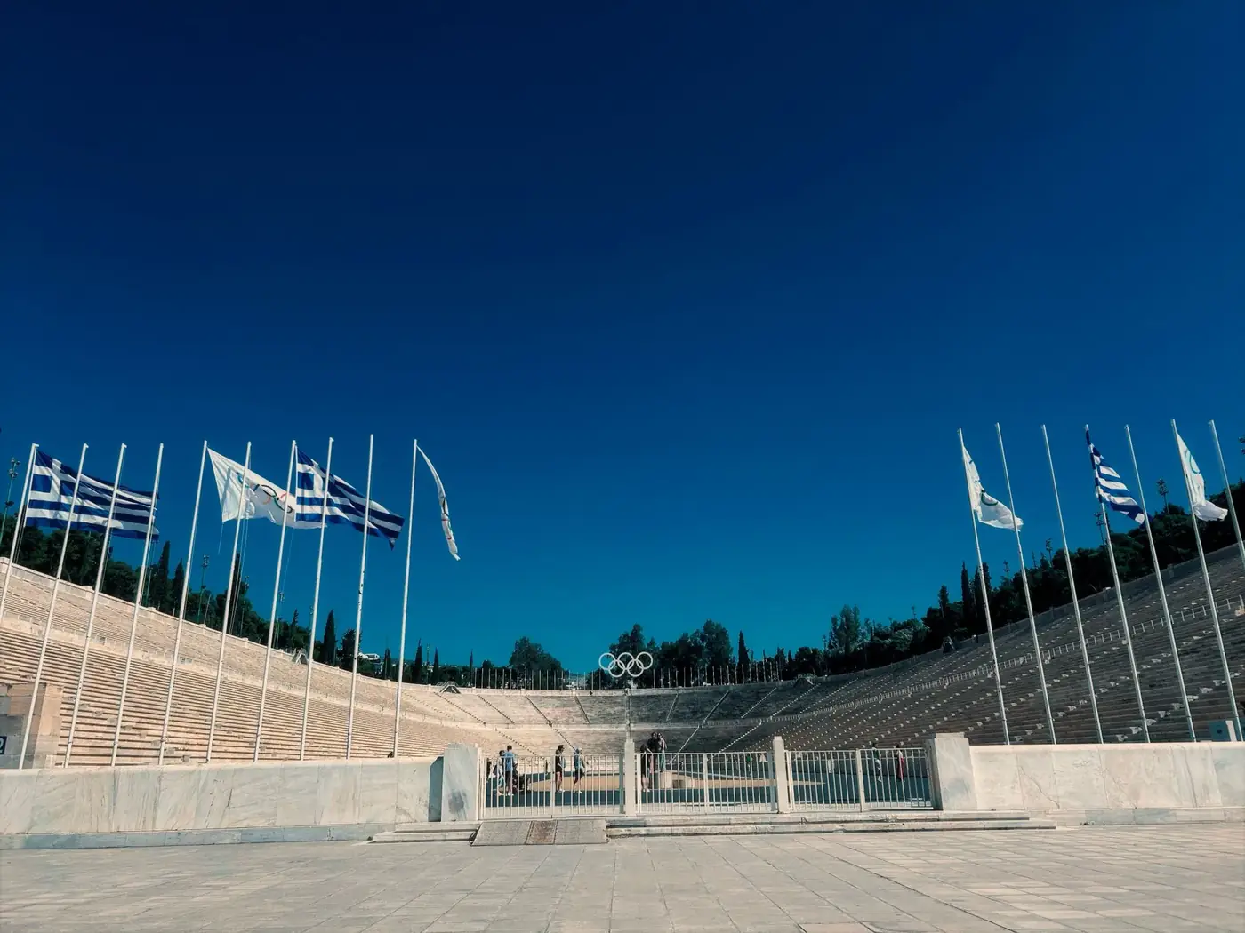 Panathenaic Stadium in Athens, Greece, featuring rows of flags under a clear blue sky.