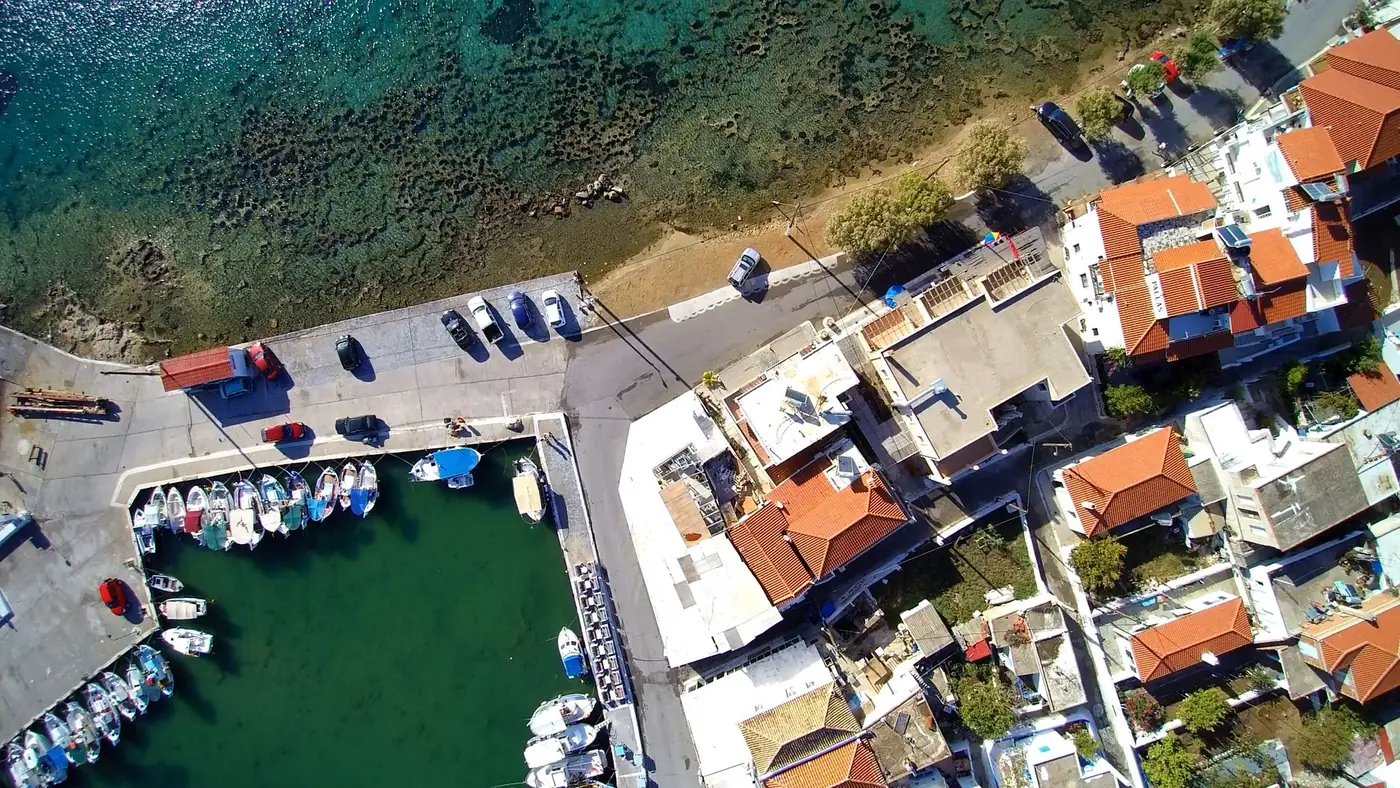 Aerial shot of a coastal town with boats in a harbor and buildings lining the shore.