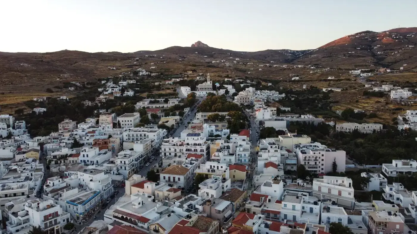 Charming aerial vista of Tinos, Greece, showcasing traditional whitewashed buildings under a serene sky.