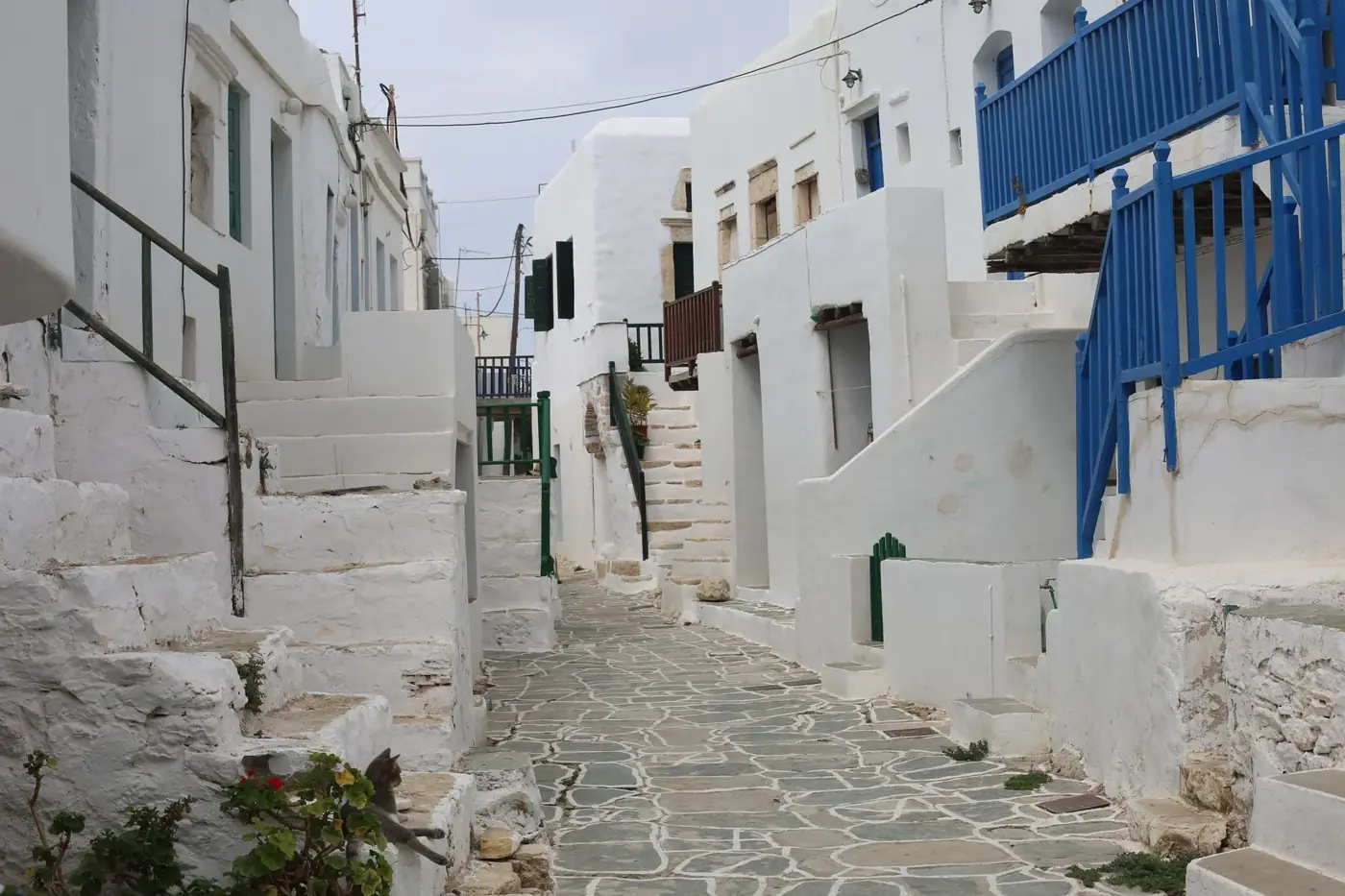 Picturesque alleyway on a Greek island with iconic white buildings and blue accents.