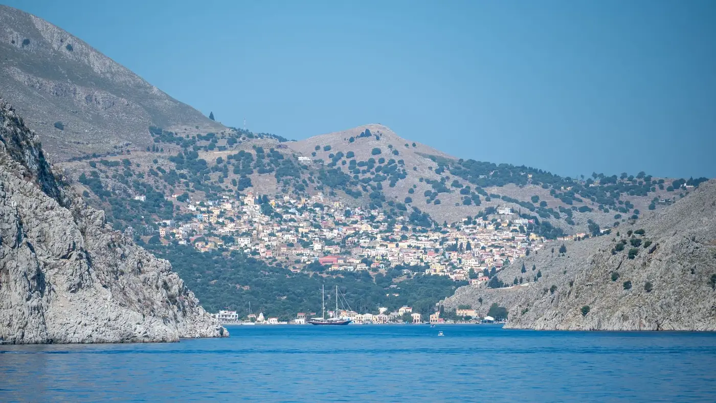 Picturesque Mediterranean hillside village by the sea, surrounded by rocky cliffs and blue waters.