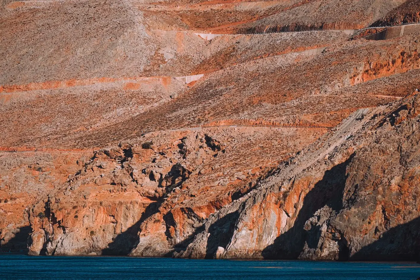 Stunning view of red cliffs and calm blue waters, capturing natural beauty and tranquility in an arid landscape.