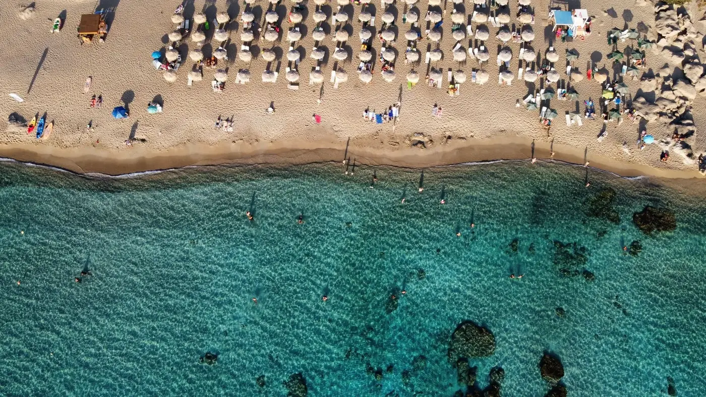Aerial view of Chania beach, Greece with umbrellas and turquoise water.