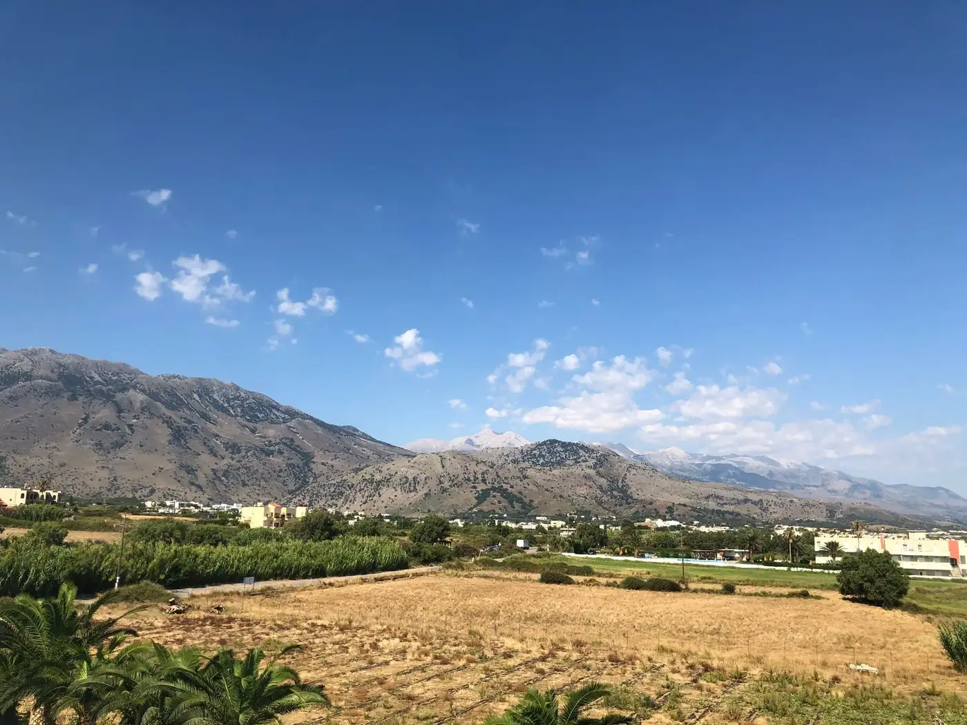 Beautiful rural landscape with cropland and majestic mountains under a clear blue sky.