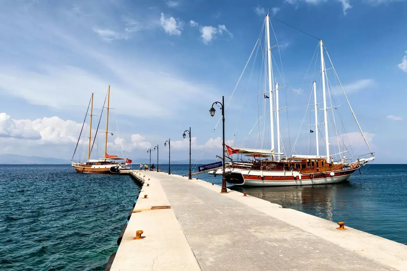 Sailboats moored at a scenic pier in Kos, Greece under a bright summer sky.