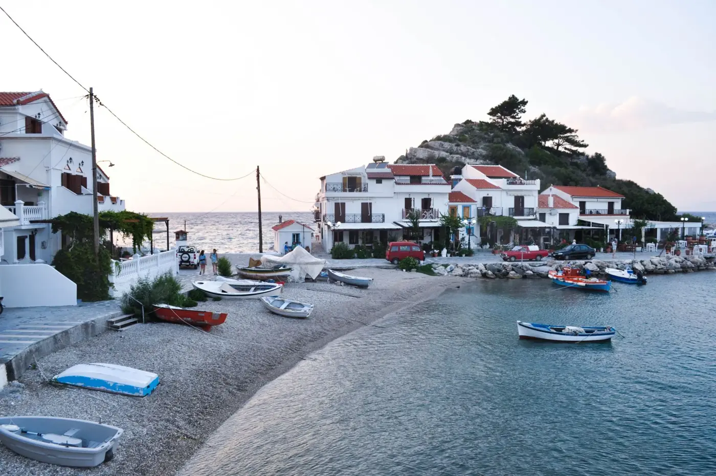 Charming coastal village in Samos, Greece, at sunset with boats and traditional architecture.