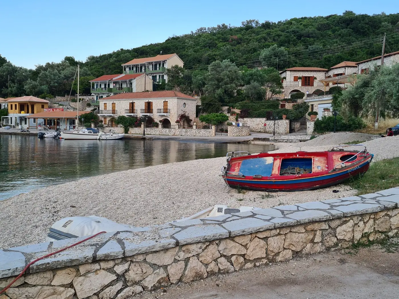 Charming Greek village with boats by a peaceful beach. Idyllic island setting.