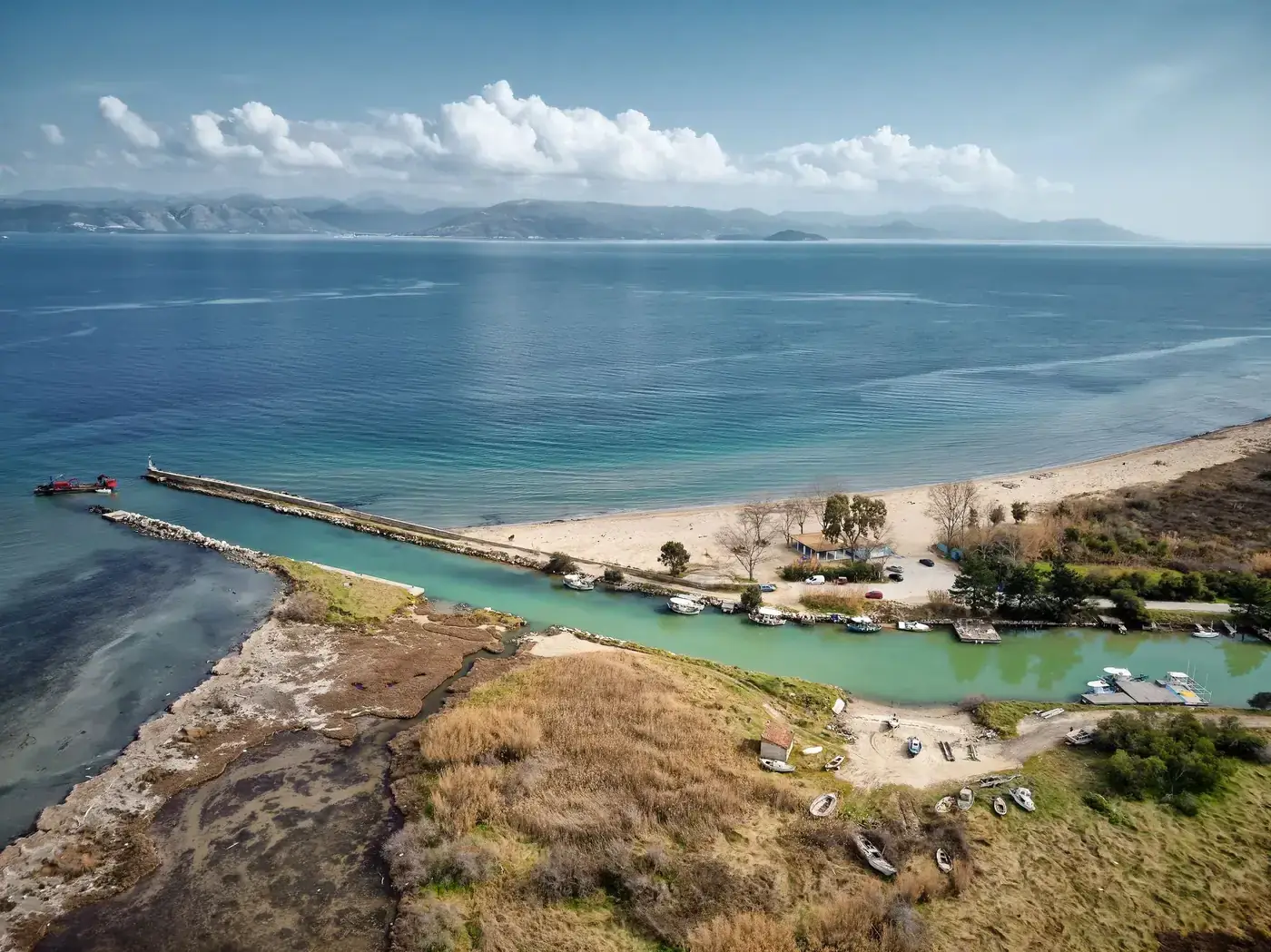 A peaceful aerial photograph of a Greek beach with clear blue waters and mountainous background, ideal for travel and na