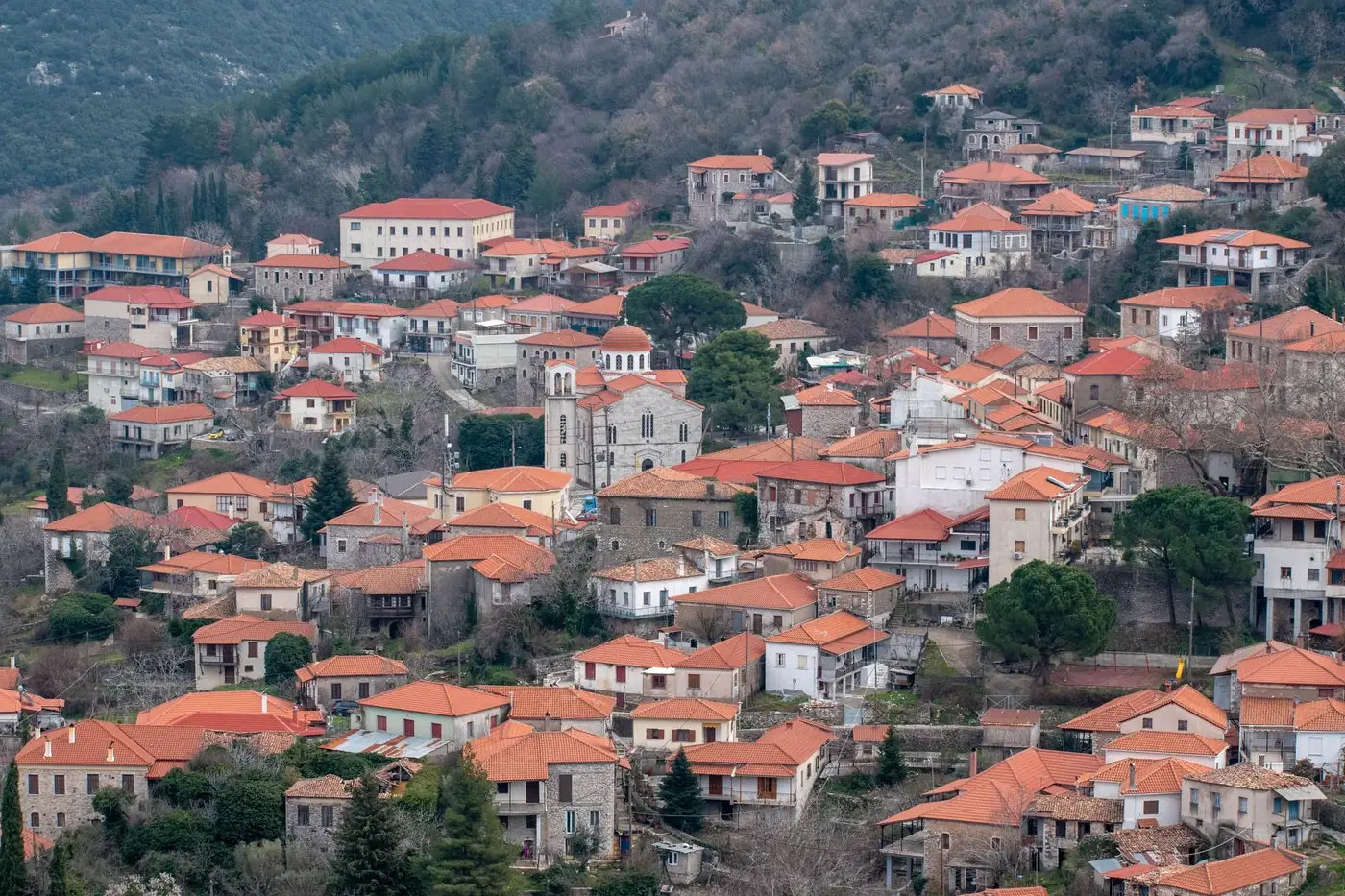 Picturesque aerial view of Andritsaina, Greece with traditional red-roofed houses nestled in a hilly landscape.
