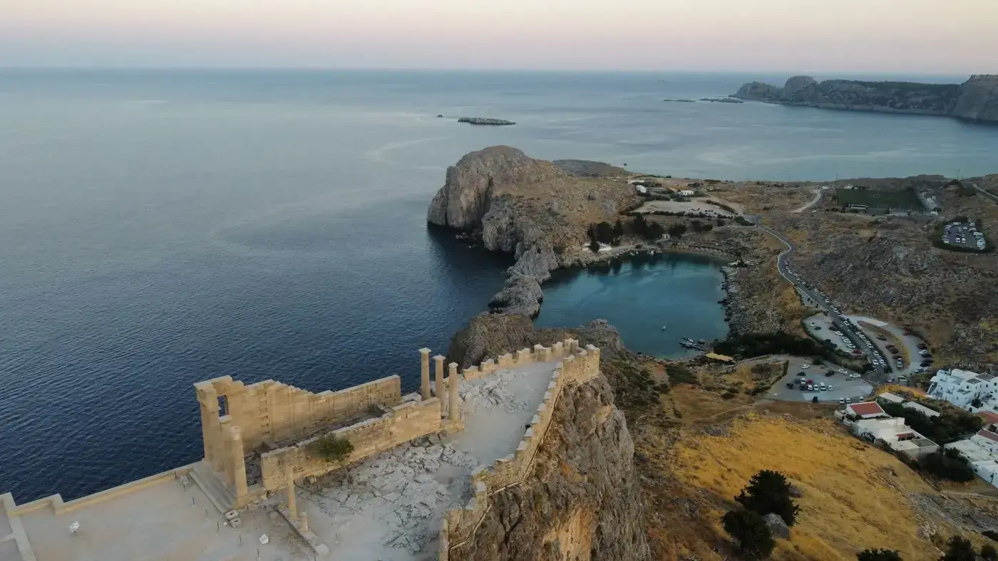 Discover the majestic ancient fortress overlooking a stunning coastline at sunset.