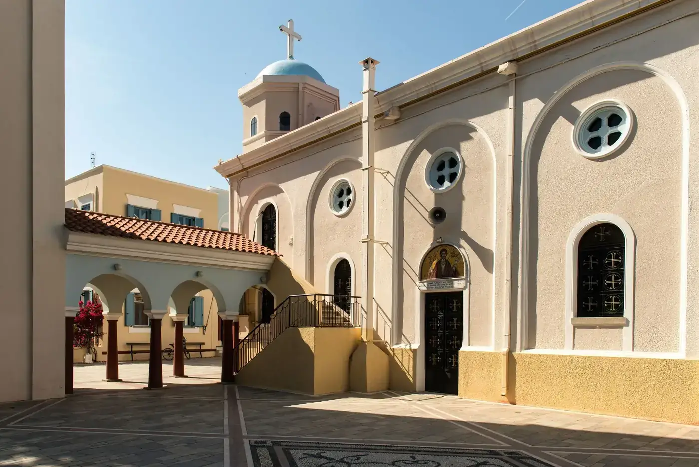 A serene courtyard of an Orthodox church in Kos, Greece with traditional architecture.